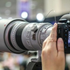 A pair of hands holding a long lens camera