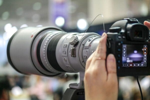 A pair of hands holding a long lens camera