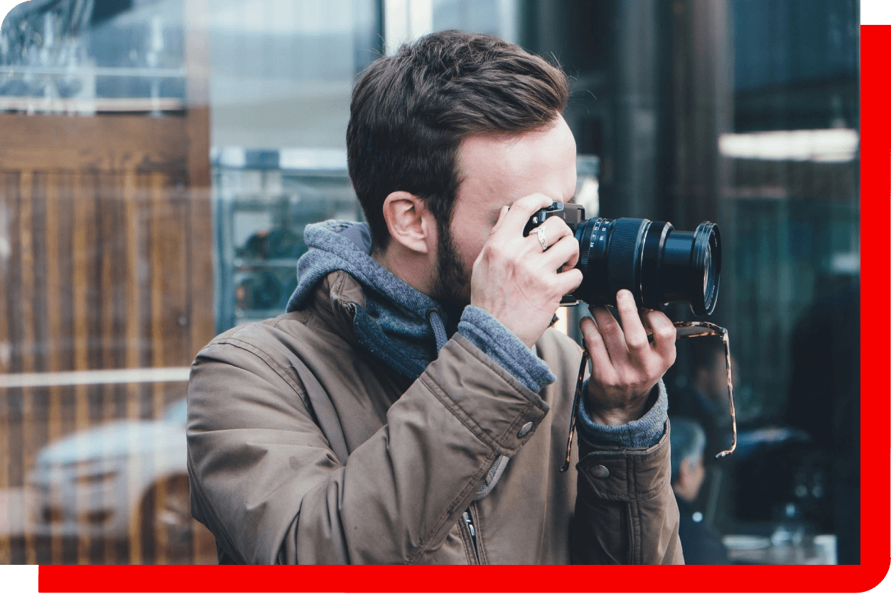 Man in brown jacket taking photo with camera.