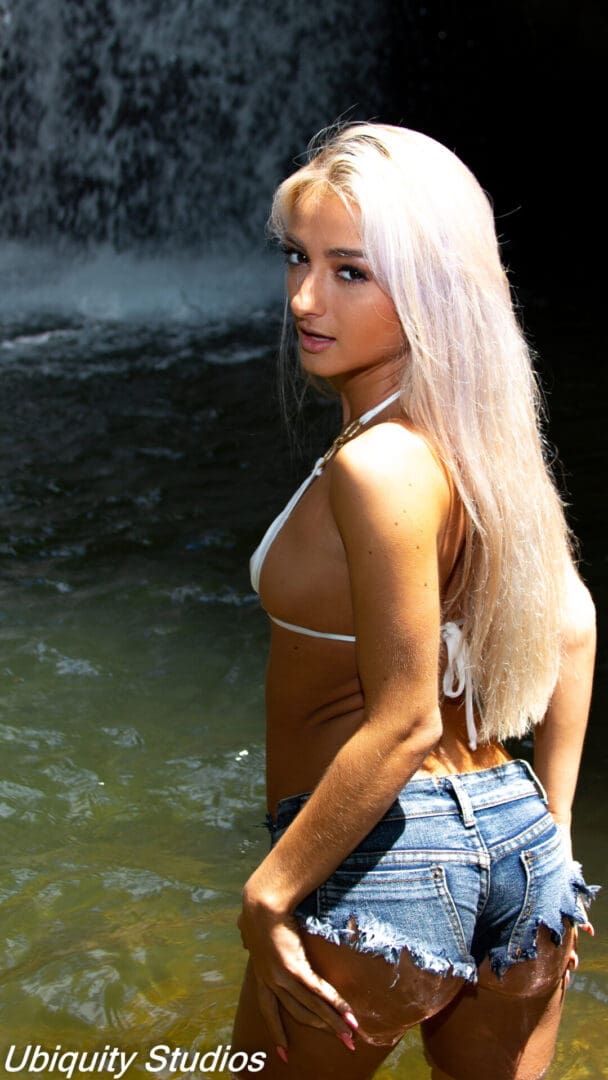 Woman in denim shorts by a waterfall.