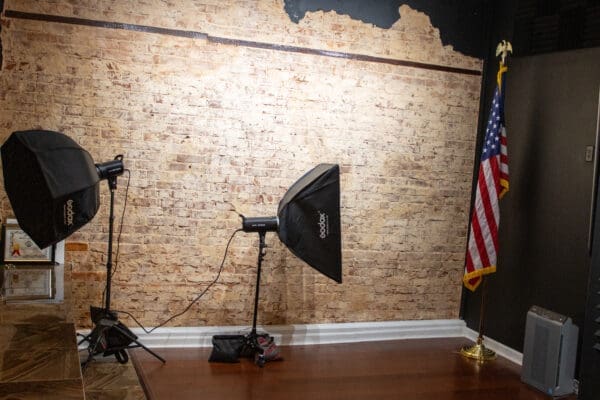 Two studio lights against brick wall with flag.