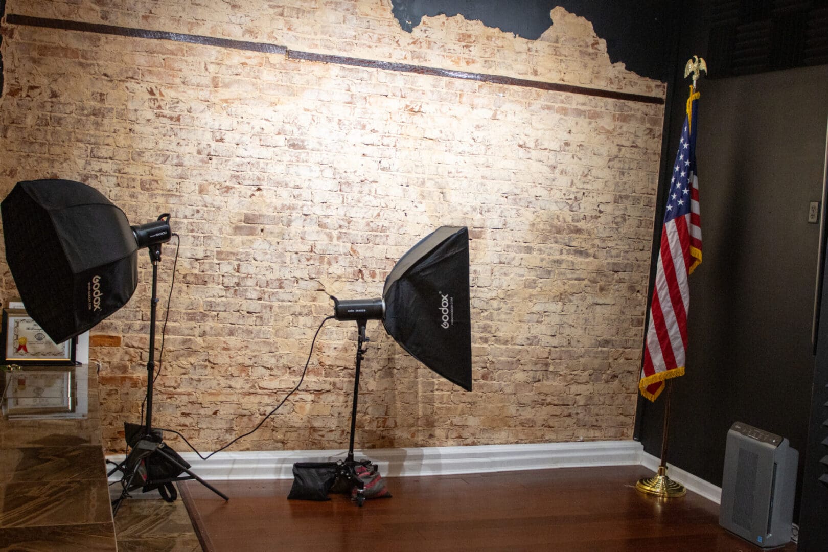 Two studio lights against brick wall with flag.